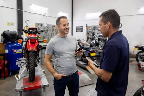 latin american man making a mobile payment at a motorcycle repair shop